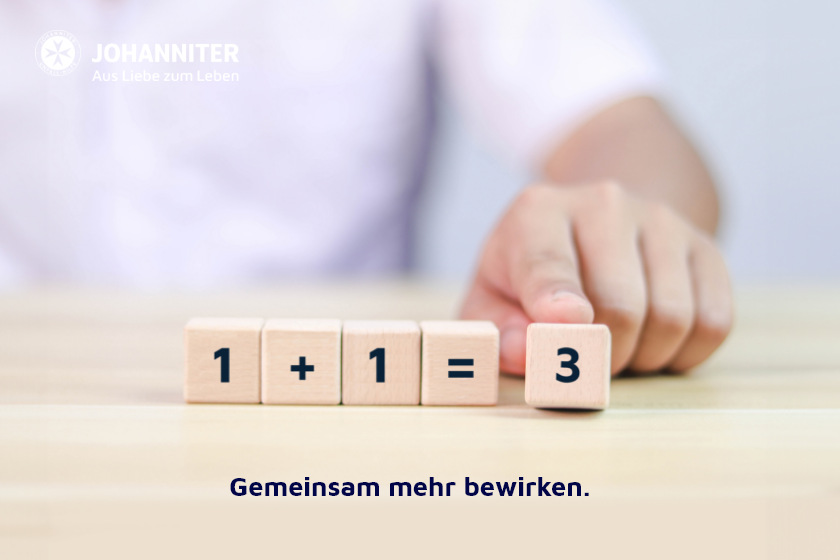 Holzklötze mit der Rechnung 1 + 1 = 3. Eine Hand schiebt den letzten Klotz mit der Zahl 3 nach vorne.