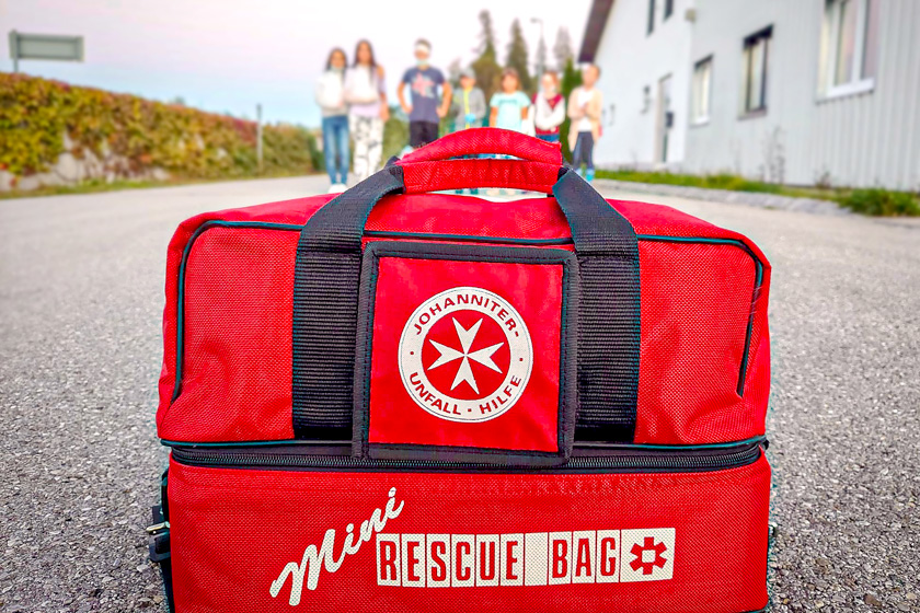 Mehrere Kinder laufen auf eine rote Johanniter Mini Rescue Bag zu.