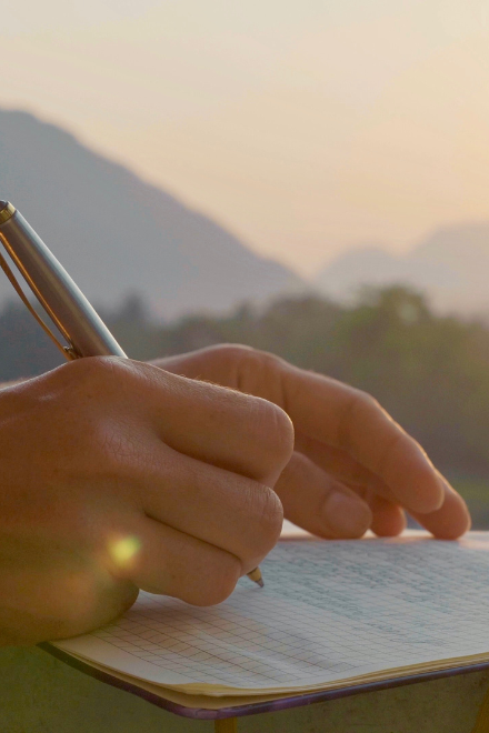 Nahaufnahme von Händen, die einen Stift halten und auf Papier schreiben als Symbol für Erfahrungsberichte in der Klinik am Korso