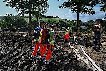 Rettungskräfte der Johanniter sprechen mit einer Betroffenen im Ahrtal.