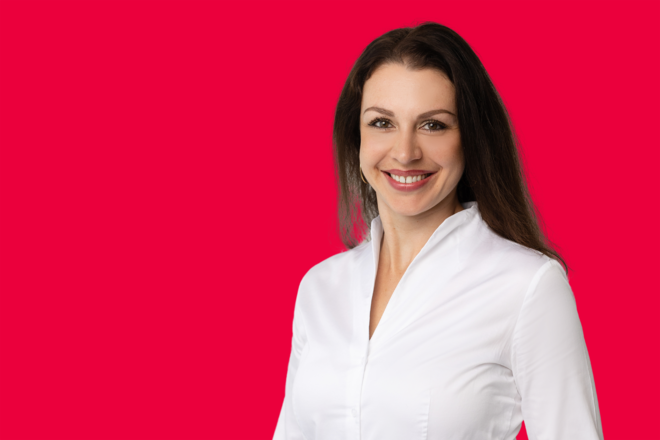 Portrait einer Mitarbeiterin vor rotem Hintergrund
