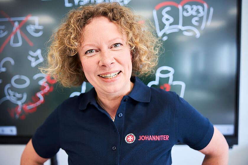 Eine Erste-Hilfe-Trainerin der Johanniter steht vor einem Smartboard.
