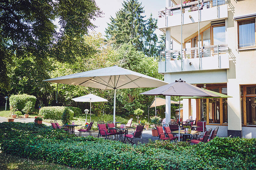 Sonnenschirme, Gartenmöbel mit roten Sitzauflagen im Außenbereich Johanniterhaus Sinzig