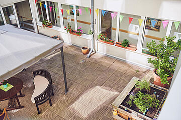 Angelegte Blumen-, Planzkästen und Gartenmöbel im Innenhof laden zum Treffen im Johanniter-Stift Köln Ehrenfeld.