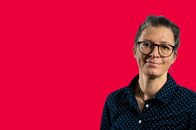 Portrait einer Mitarbeiterin vor rotem Hintergrund