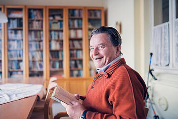Ein Mann liest in der Bibliothek ein Buch
