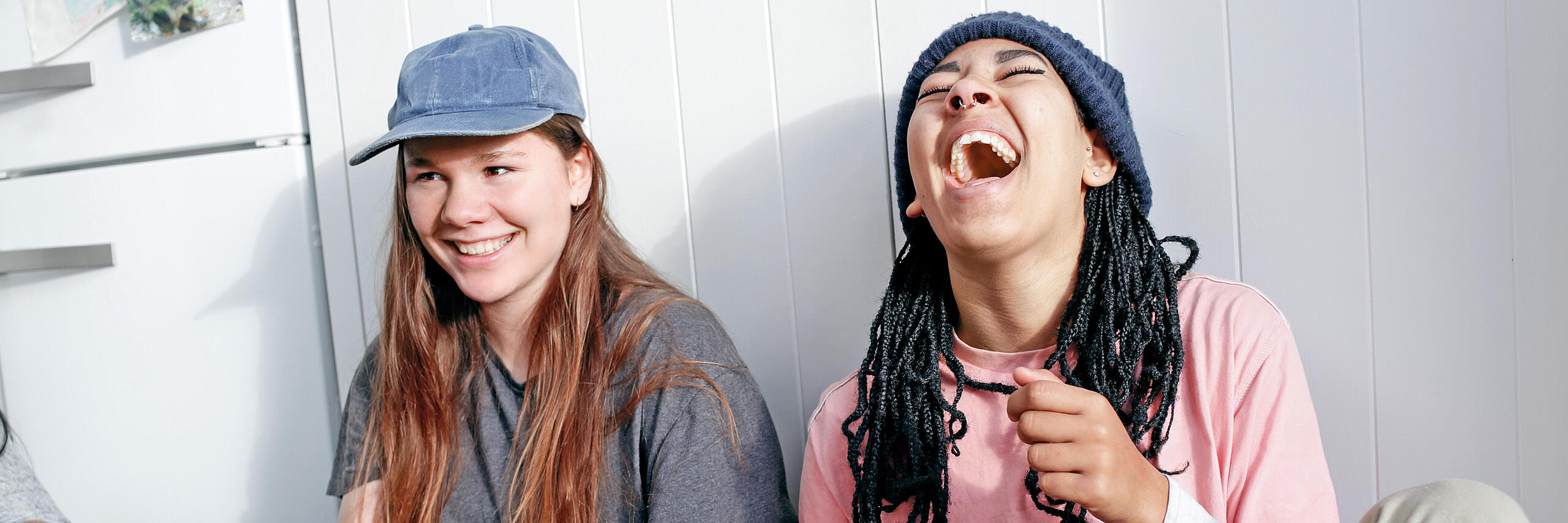 Zwei FSJlerinnen sitzen vor einer Wand und lachen