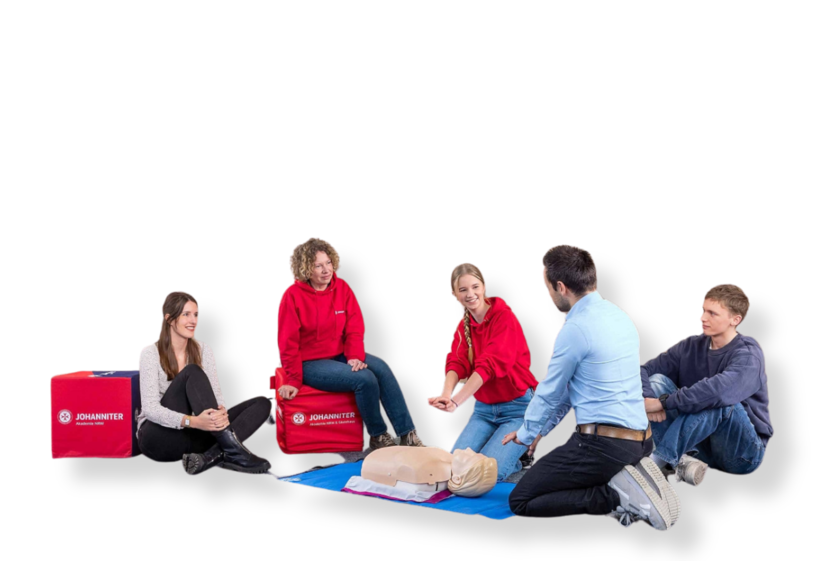 Erste-Hilfe-Trainer erklärt Teilnehmenden Wiederbelebungsmaßnahmen anhand Übungspuppe