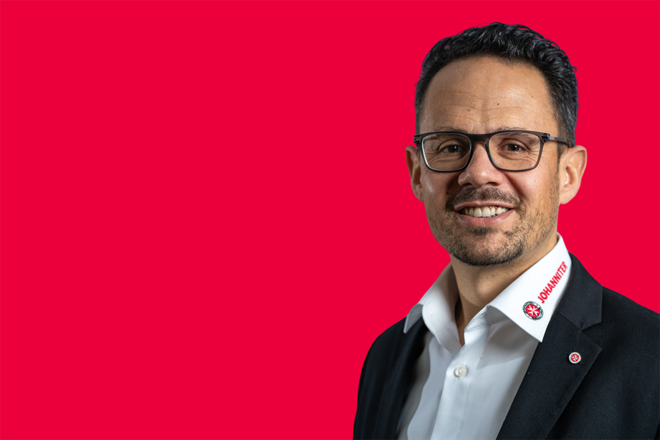 Portrait eines Mitarbeiters vor rotem Hintergrund