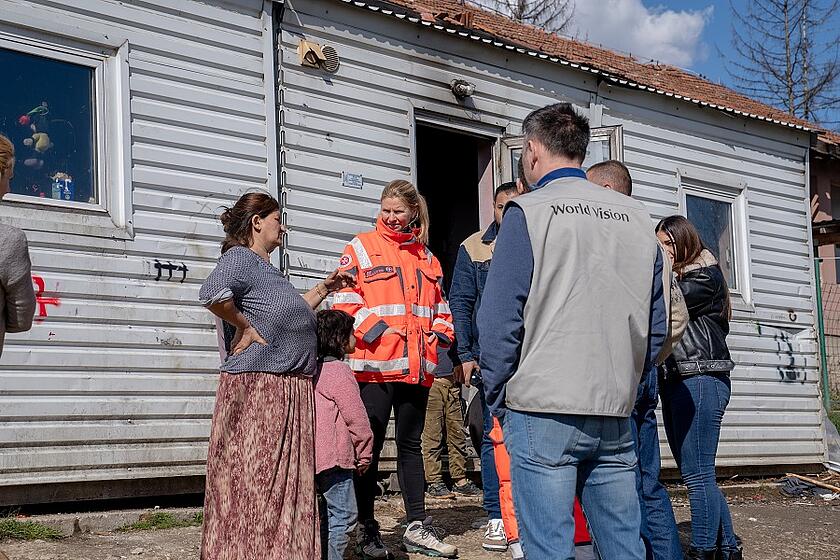 Eine Mitarbeiterin der Johanniter unterhält sich mit einer Familie vor ihrem Haus