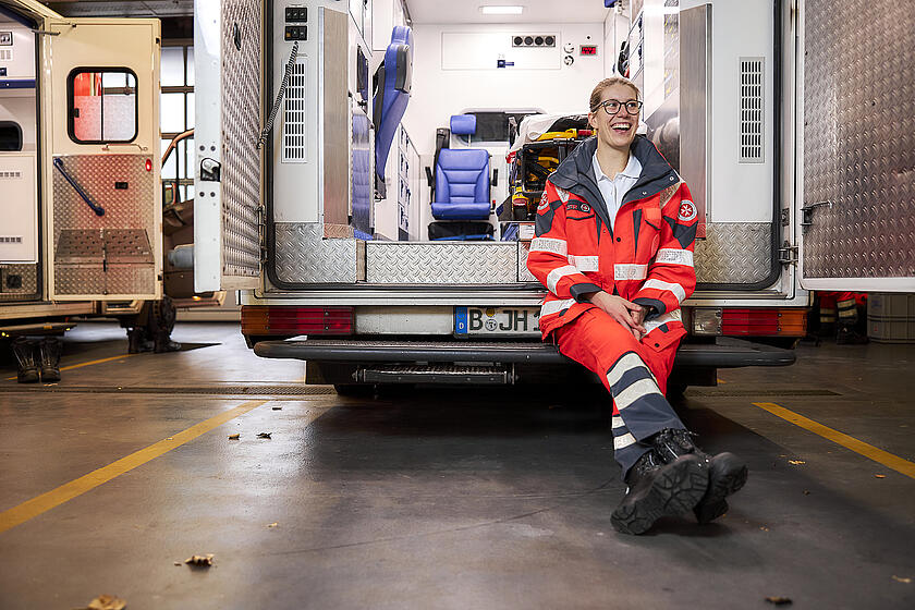 Sanitäterin sitzt in geöffnetem Rettungswagen und ruht sich aus