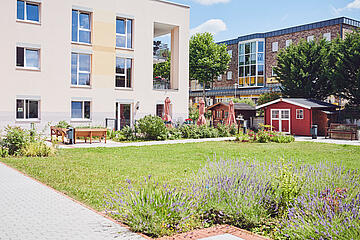 Blick auf die Fassade mit Sitzgelegenheiten und schönen Grünflächen davor