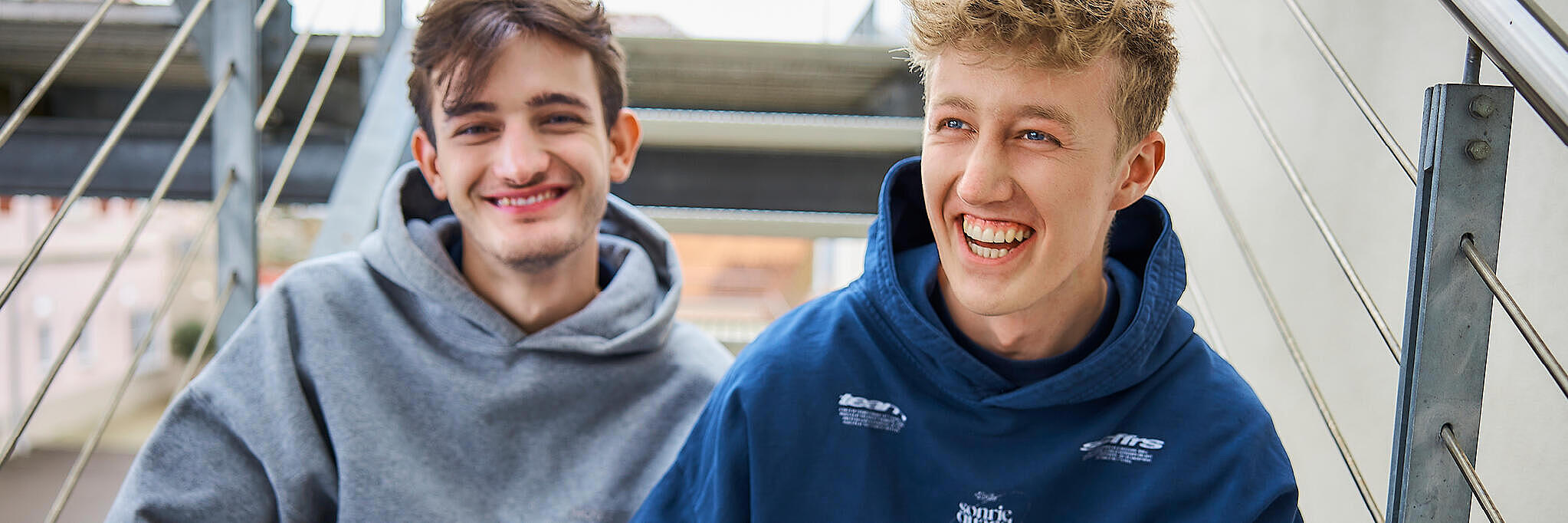 Zwei FSJler sitzen auf einer Treppe und lachen