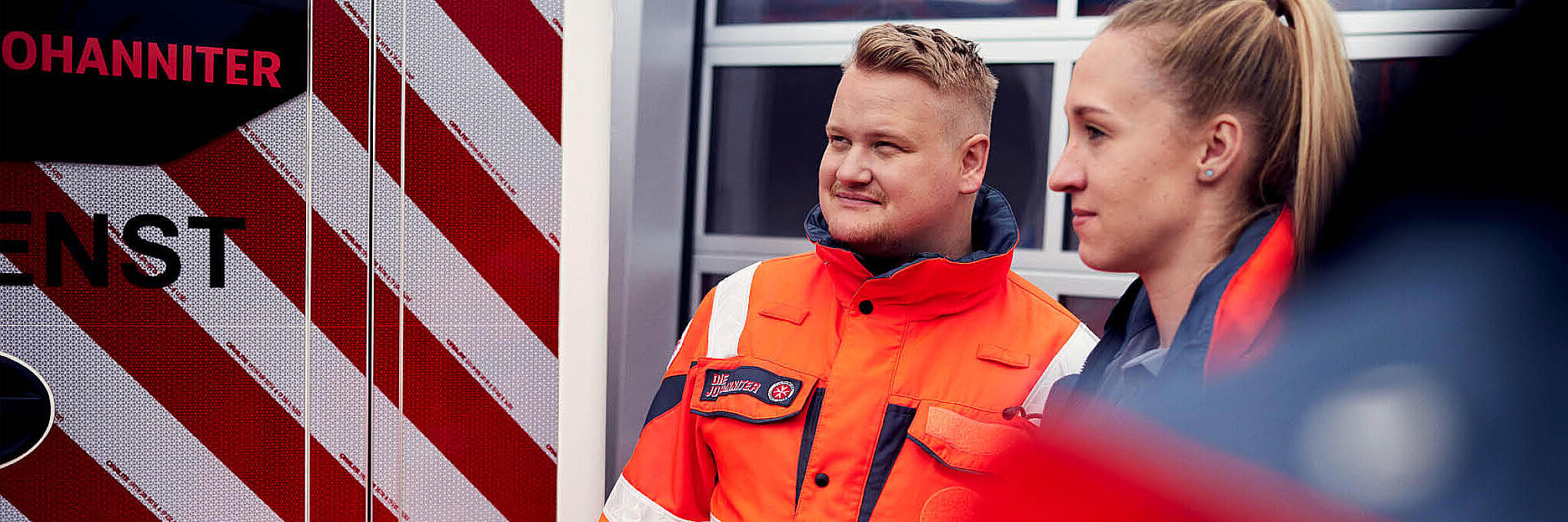 Zwei Einsatzkräfte stehen vor einem Rettungswagen der Johanniter