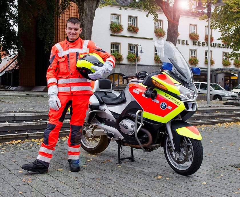 Ein Mann steht mit seinem Helm neben seinem Motorrad