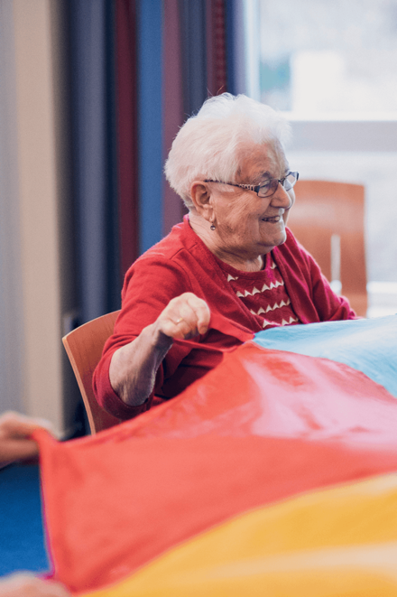 Bewohnerinnen bewegen sich mit einem bunten Schwungtuch