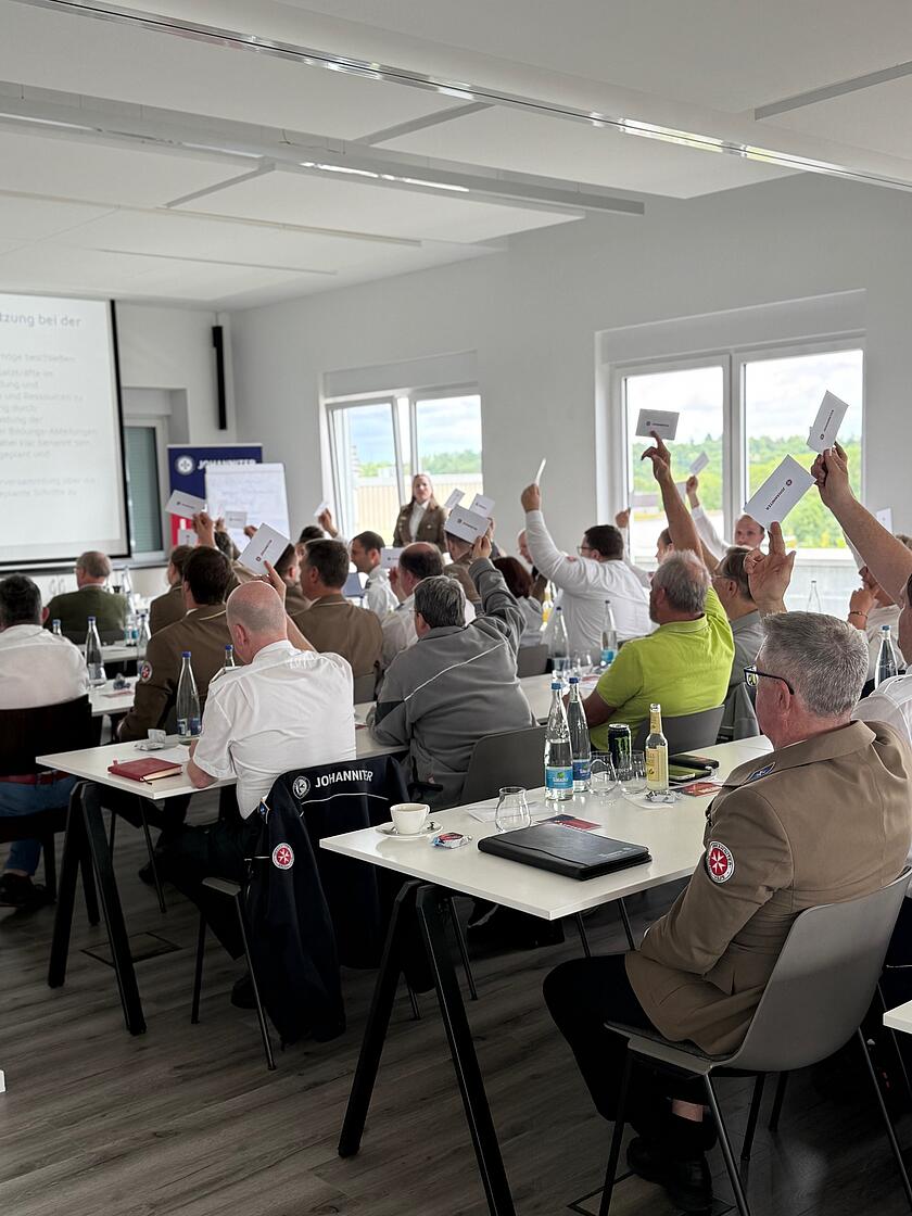 Teilnehmende der Landesvertreterversammlung stimmen mit Handzeichen ab