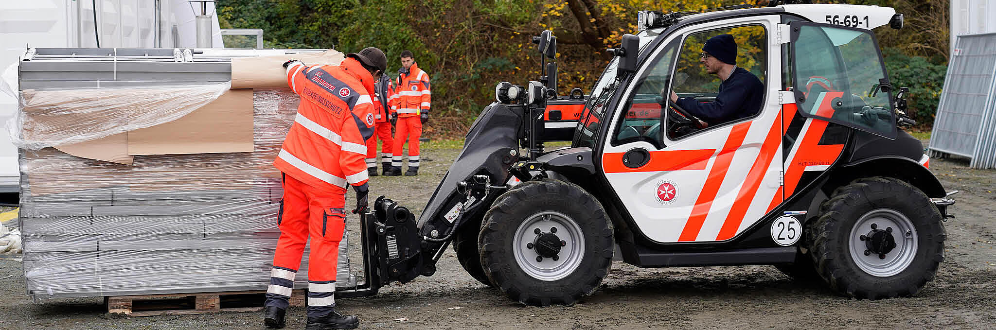 Eine Person hilft Material auf einem Johanniter-Ladekran festzumachen