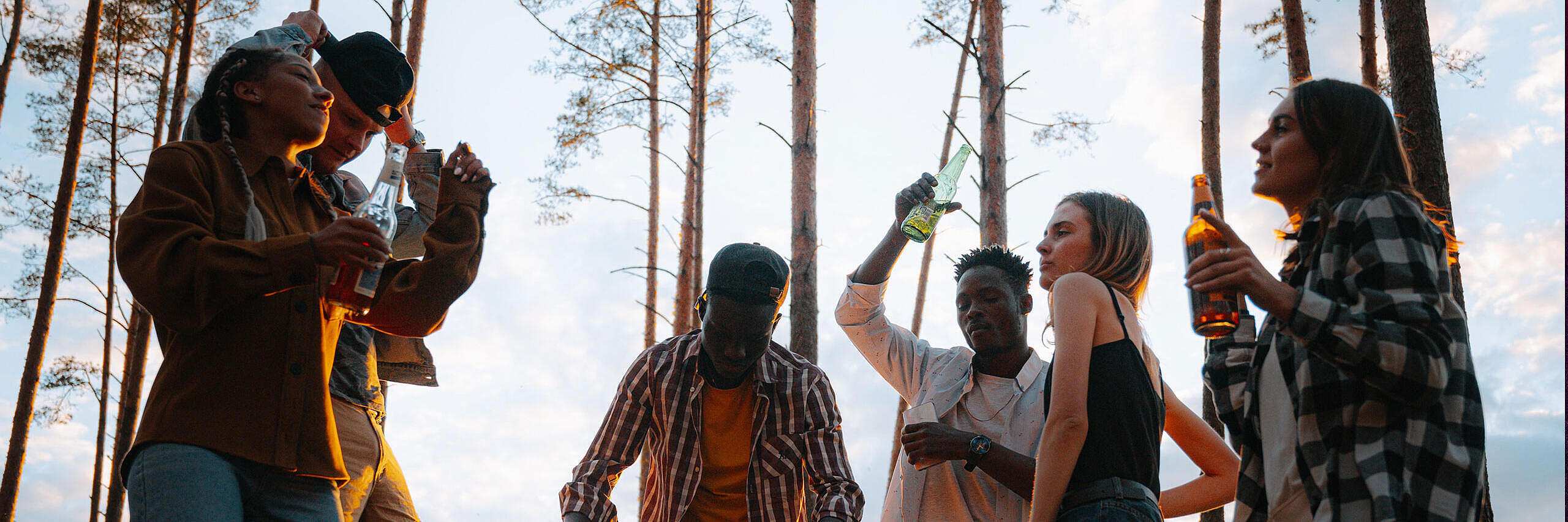 Mehrere junge Menschen feiern im Wald.